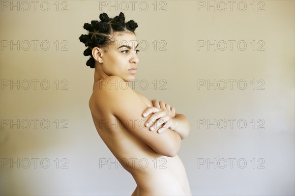 Naked Mixed Race woman with arms crossed