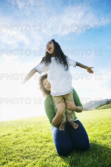 Mixed race mother holding daughter pretending to be airplane