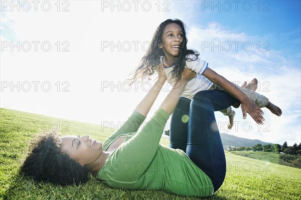 Mixed race mother lifting daughter on legs