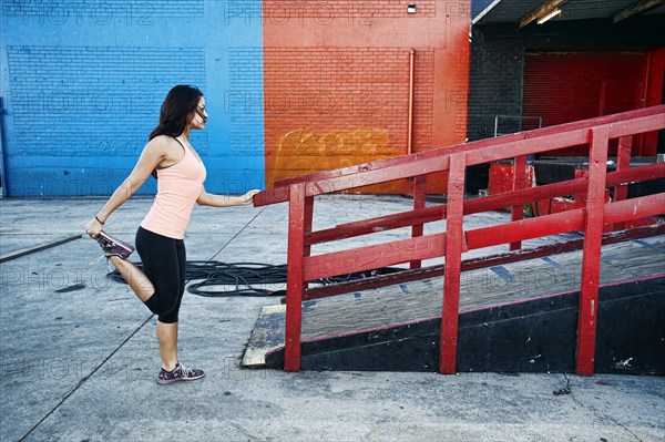 Mixed race woman stretching leg at loading dock