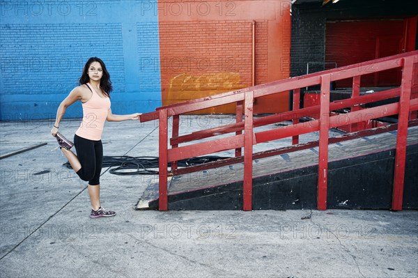 Mixed race woman stretching leg at loading dock