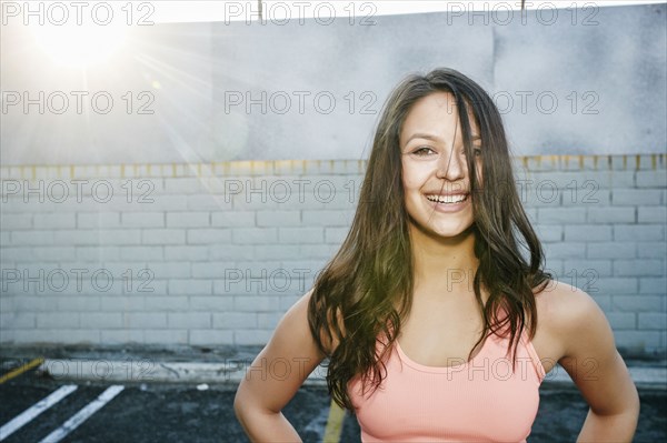 Sunbeams on smiling mixed race woman in parking lot