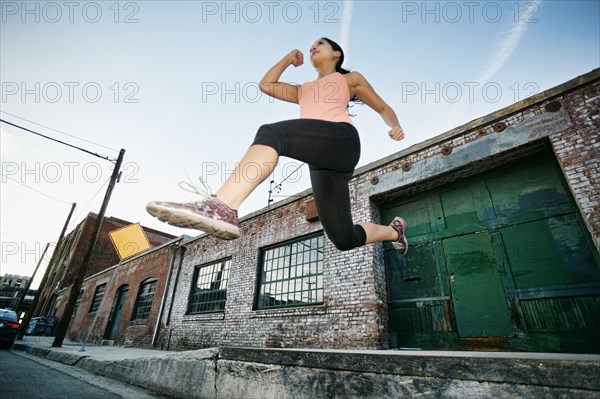 Mixed race woman jumping off loading dock