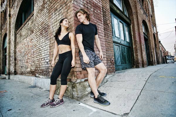 Couple leaning on corner of brick building