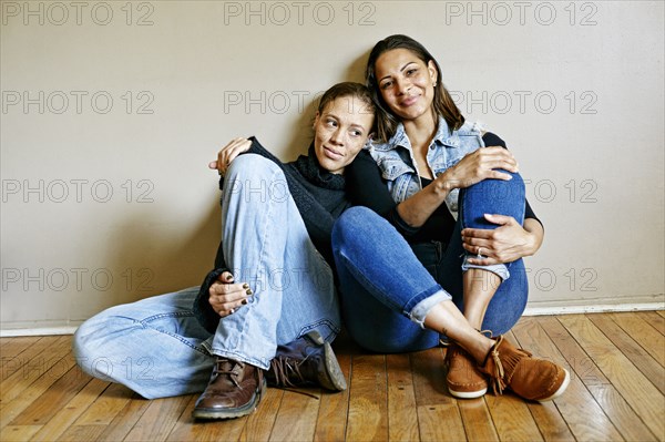 Smiling mixed race women sitting on floor