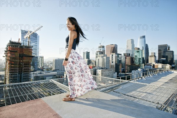 Smiling Asian woman standing on windy urban rooftop