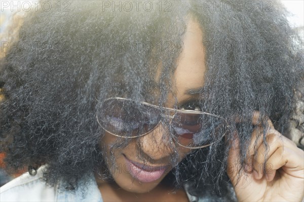 Close up of mixed race woman peering over sunglasses