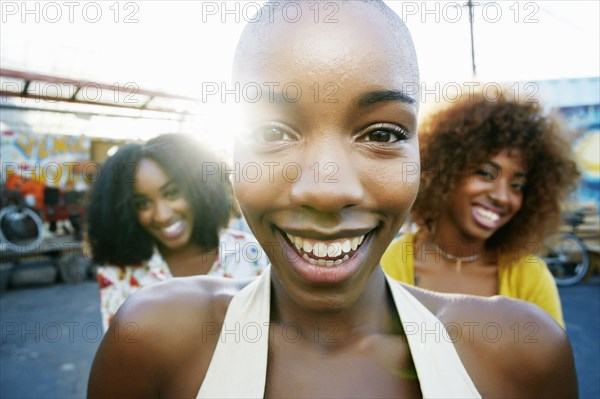 Friends smiling behind bald woman outdoors