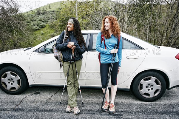 Smiling women standing near car hold and walking sticks