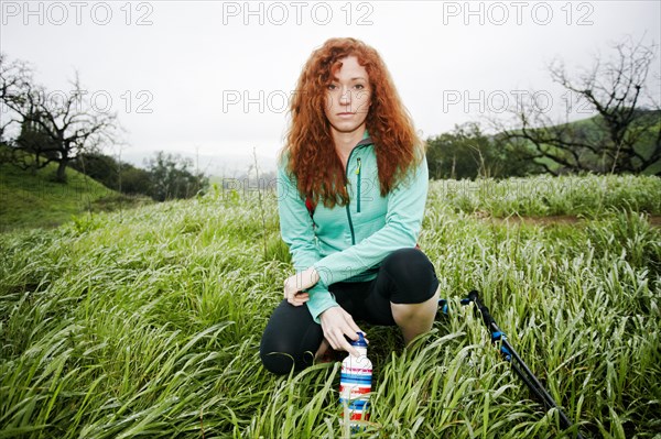 Portrait of crouching Caucasian woman holding bottle