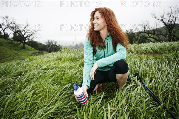 Portrait of crouching Caucasian woman holding bottle