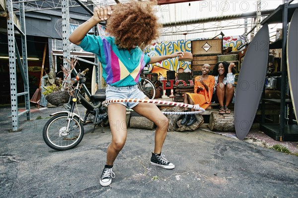 Friends watching woman spinning hoop around thighs