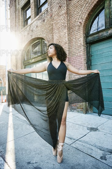 Sunbeams on mixed race woman dancing in city