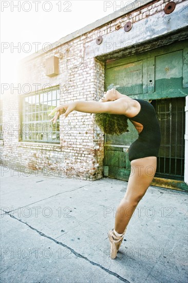 Mixed race woman dancing ballet in city