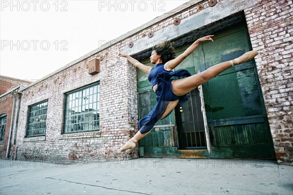Mixed race woman dancing ballet in city