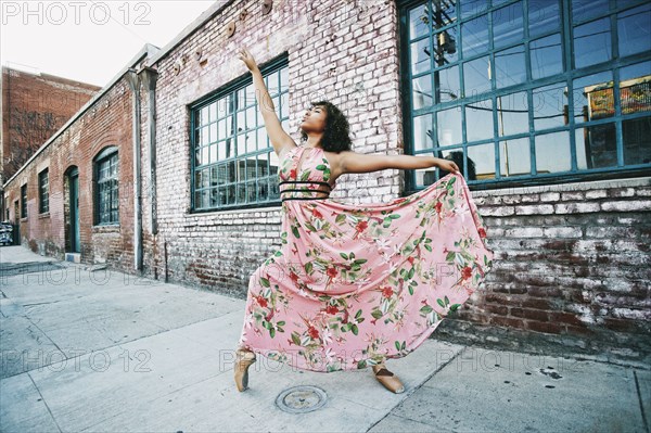 Mixed race ballet dancer wearing dress on sidewalk