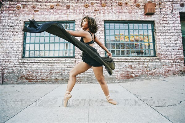 Mixed race woman dancing ballet on sidewalk