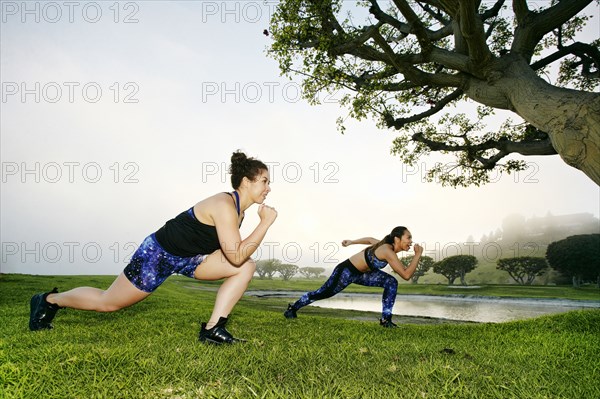 Mixed race women exercising near lake