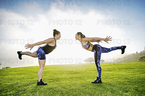Mixed race women standing on one leg in field