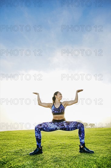 Mixed race woman squatting in field