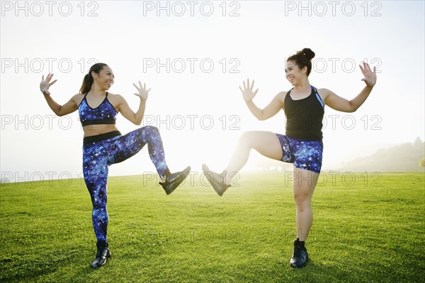 Mixed race women standing on one leg in field