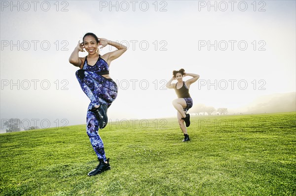 Mixed race women standing on one leg in field