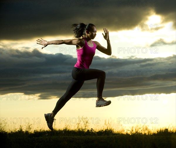 Mixed race woman running in field at night