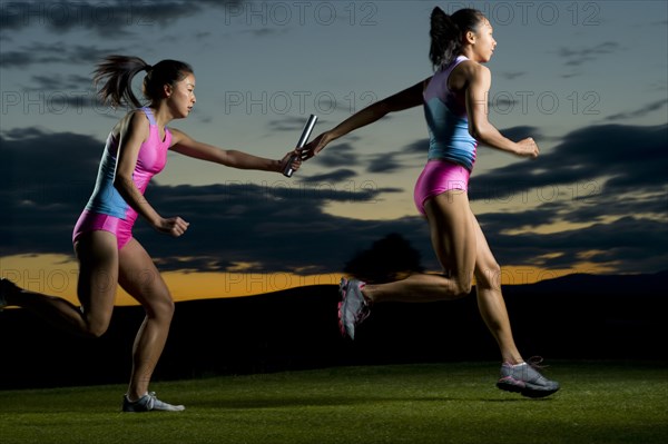 Relay runners passing baton in competition