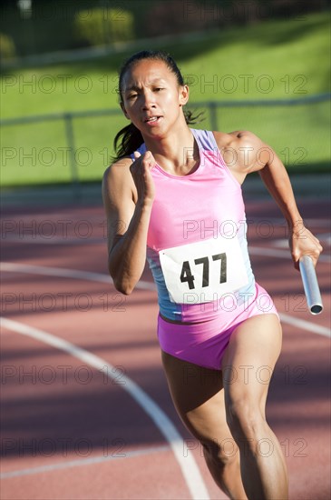 Female relay runner running with baton