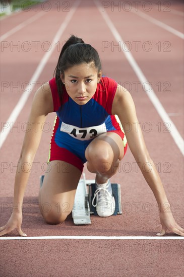 Japanese runner at starting block on racetrack