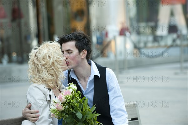 Caucasian couple kissing on bench