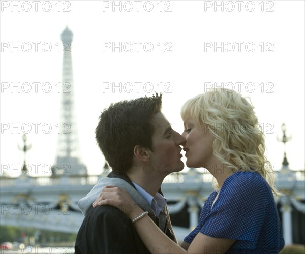 Caucasian man kissing girlfriend near Eiffel Tower