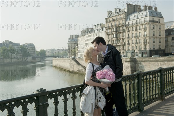 Caucasian couple kissing on bridge