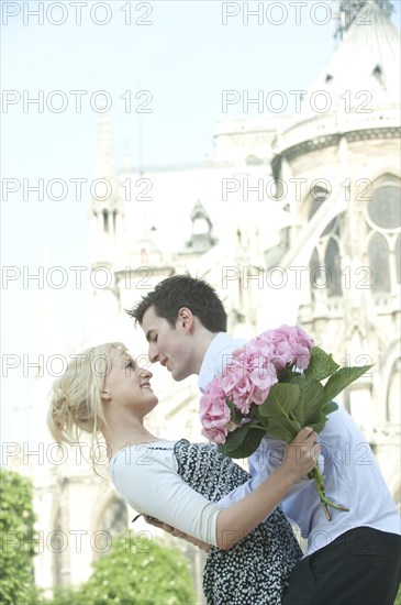 Caucasian couple about to kiss near historical landmark near Notre Dame