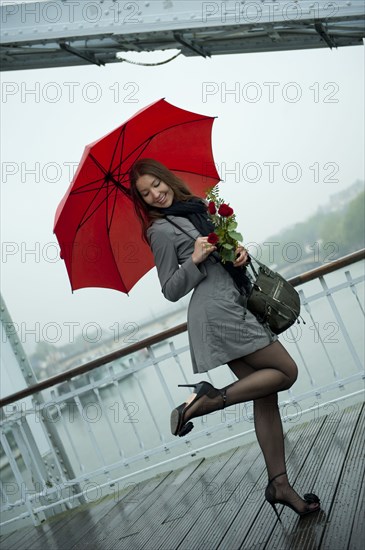 Caucasian woman in high heel shoes with red umbrella