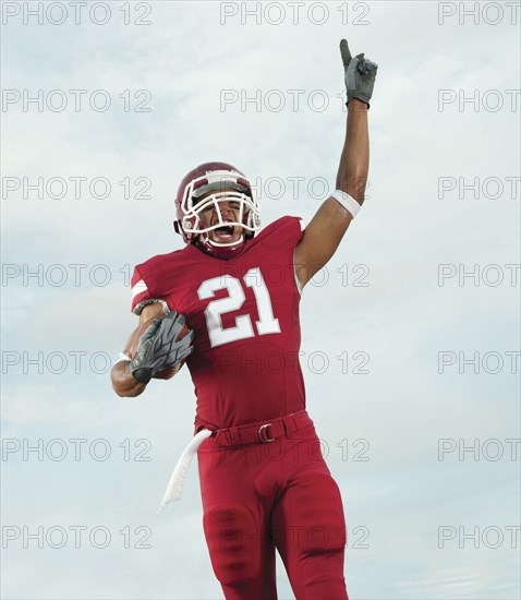 Black football player carrying football making number 1 gesture