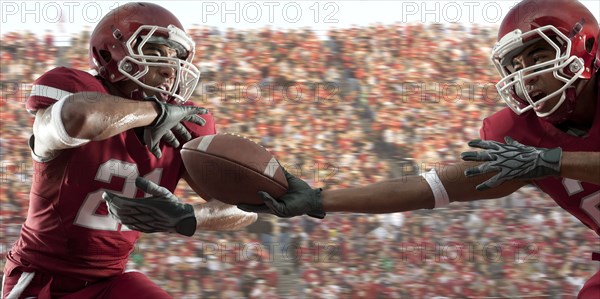 Black football player passing football to teammate