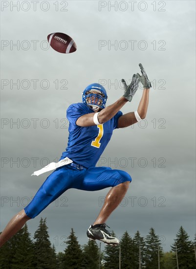 Black football player catching football player in mid-air