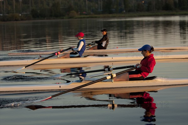 People rowing sculling boats on river