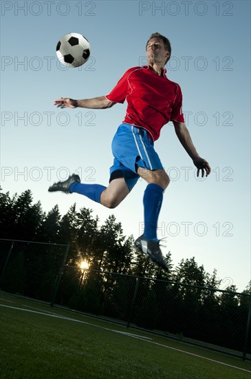 Soccer player jumping in mid-air kicking ball