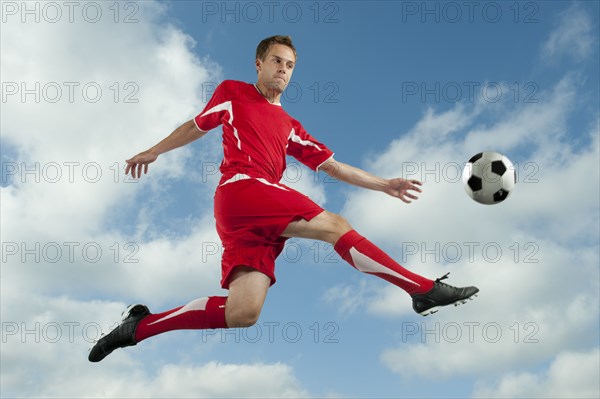 Soccer player jumping in mid-air kicking ball