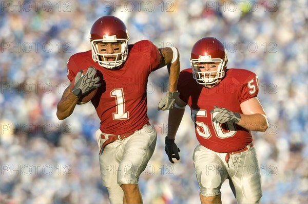 Football players running on field in game