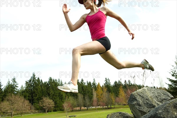 Mixed race teenager jumping from rock