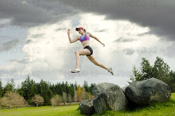 Mixed race teenager jumping from rock