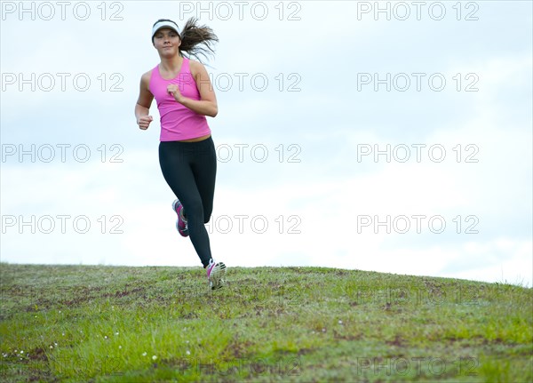 Mixed race runner jogging across field