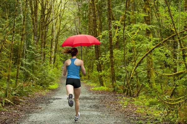 Mixed race runner training on remote road with umbrella