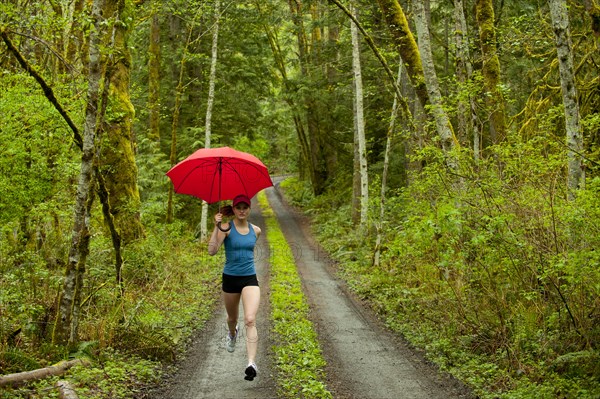 Mixed race runner training on remote road with umbrella