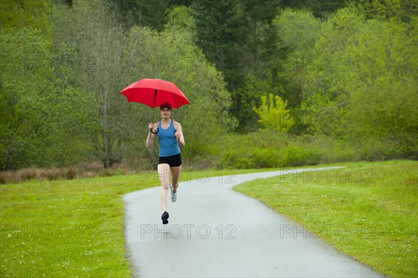 Mixed race runner training on remote road with umbrella