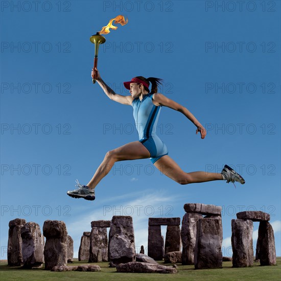 Athlete running with Olympic torch near Stonehenge