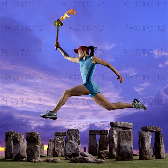 Athlete running with Olympic torch near Stonehenge